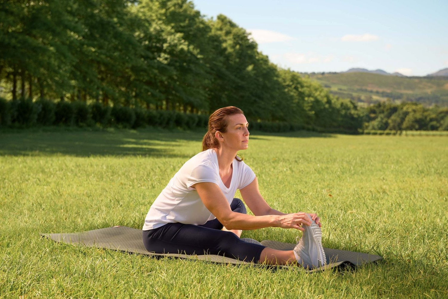 Frau macht Dehnübungen im Park