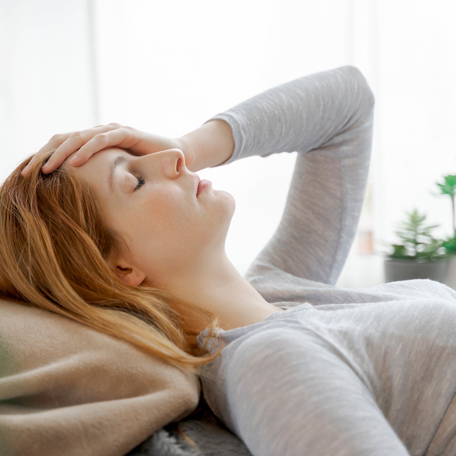 Frau liegt mit einer Migräne auf dem Sofa