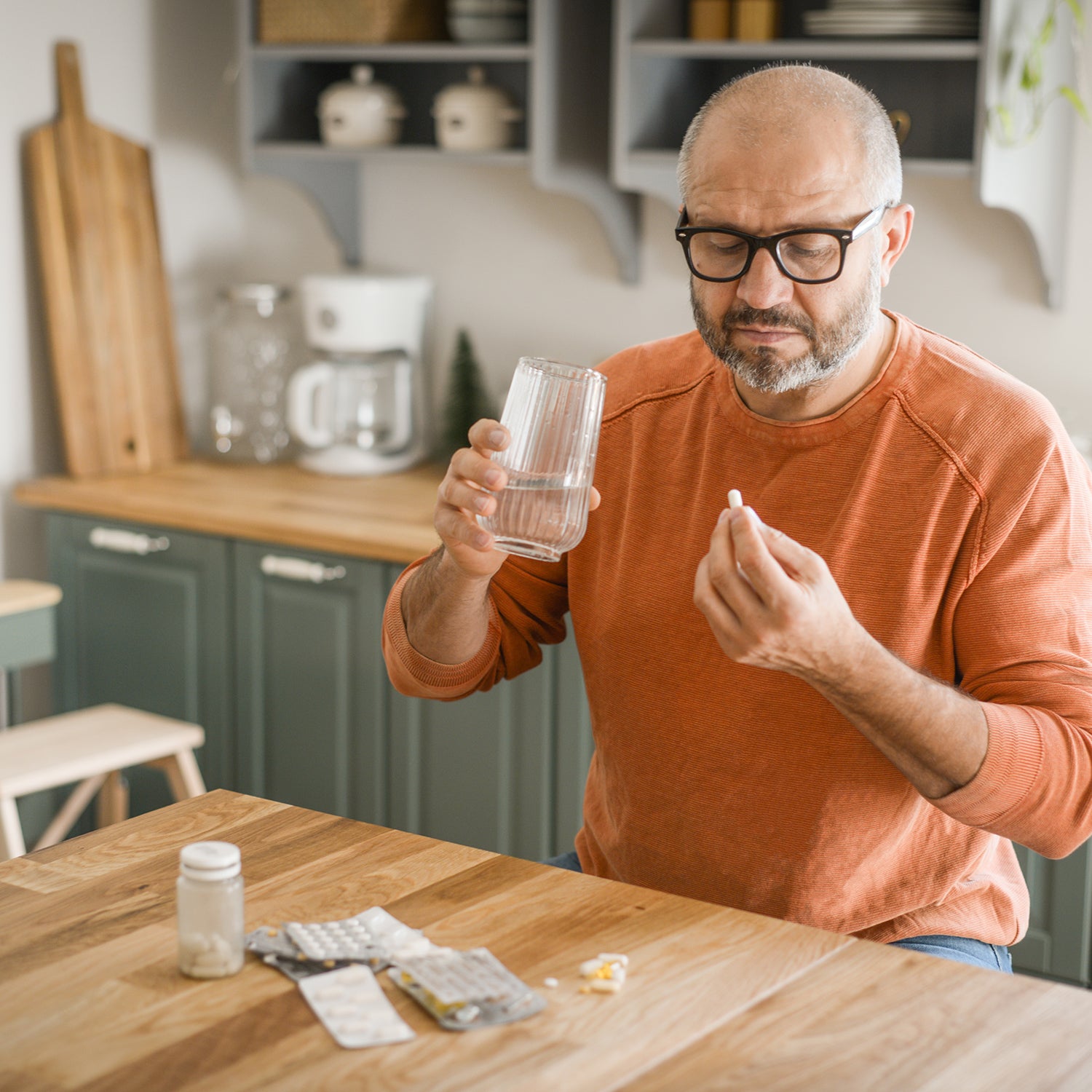 Mann nimmt Kapseln mit einem Glas Wasser ein