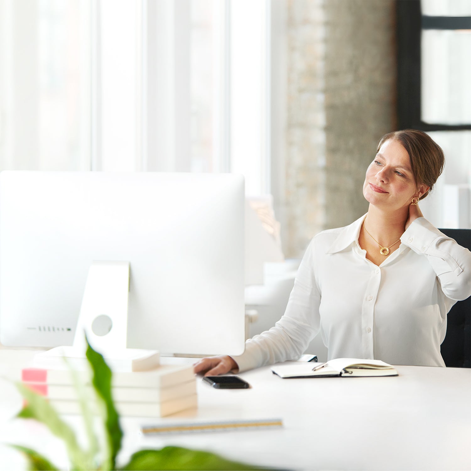 Frau massiert sich den Nacken im Büro
