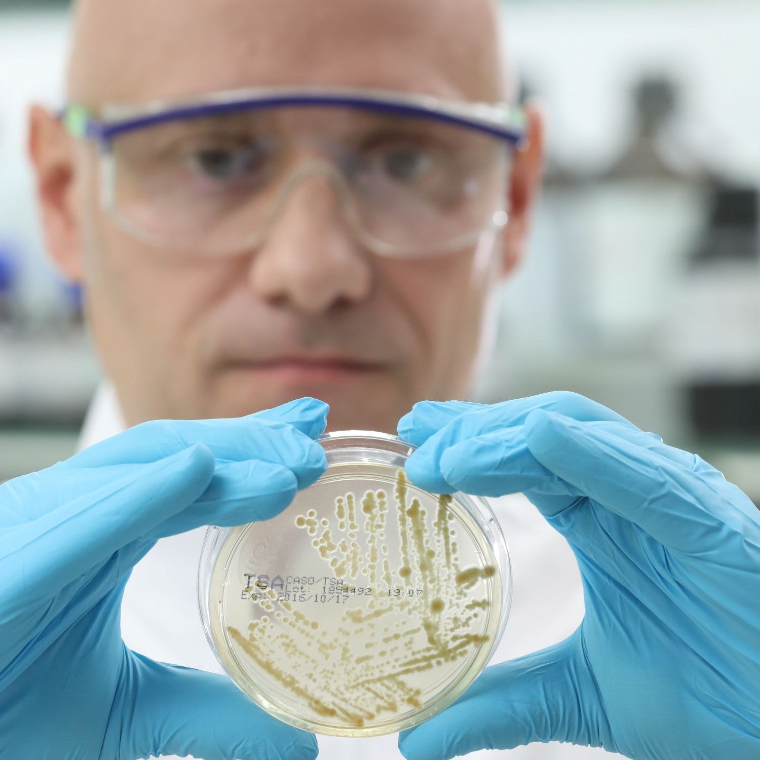 Mann mit Petrischale in den Händen