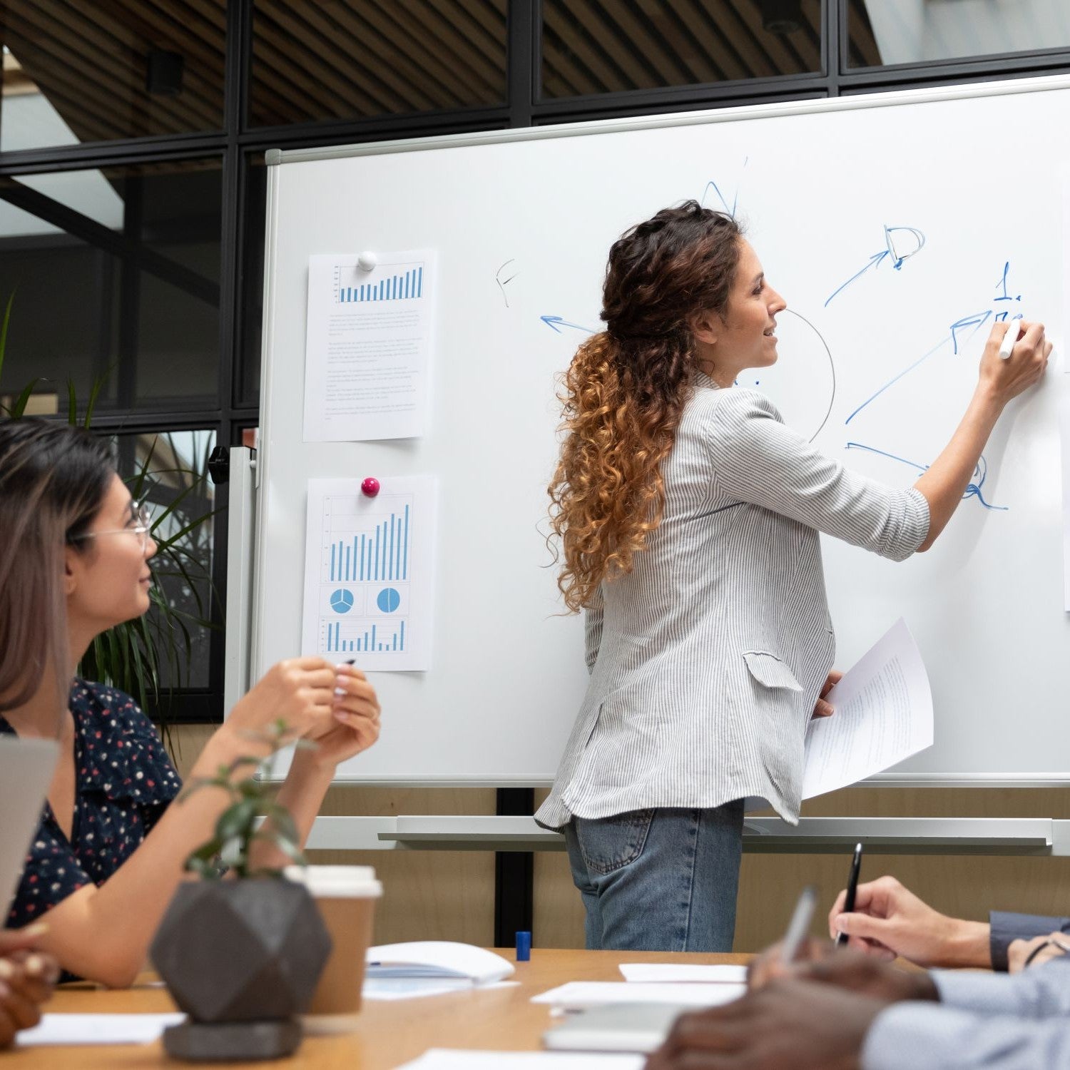 Frau schreibt bei einem Teammeeting was an ein Whiteboard