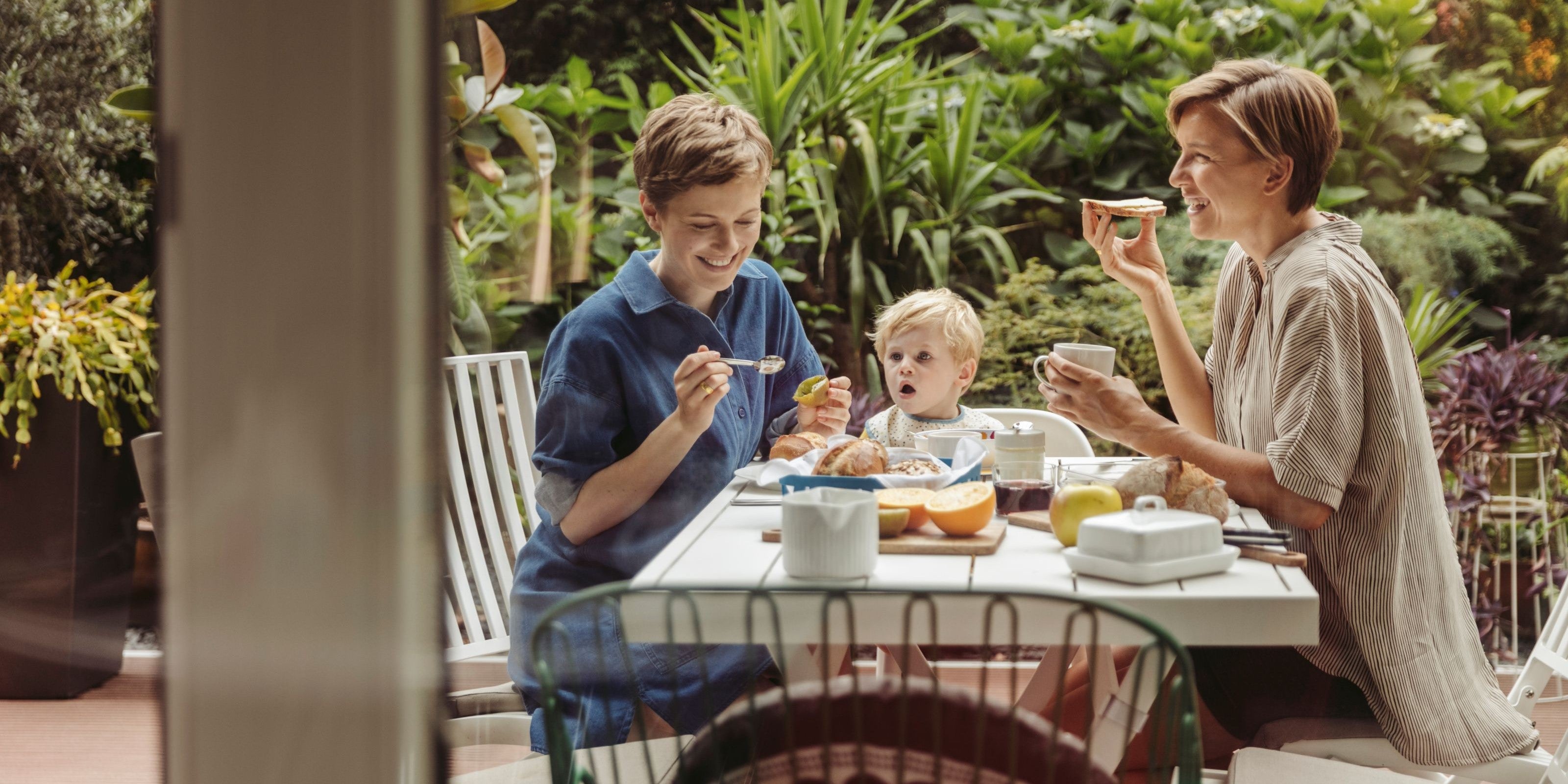 Familie sitzt zusammen am Frühstückstisch auf der Terrasse