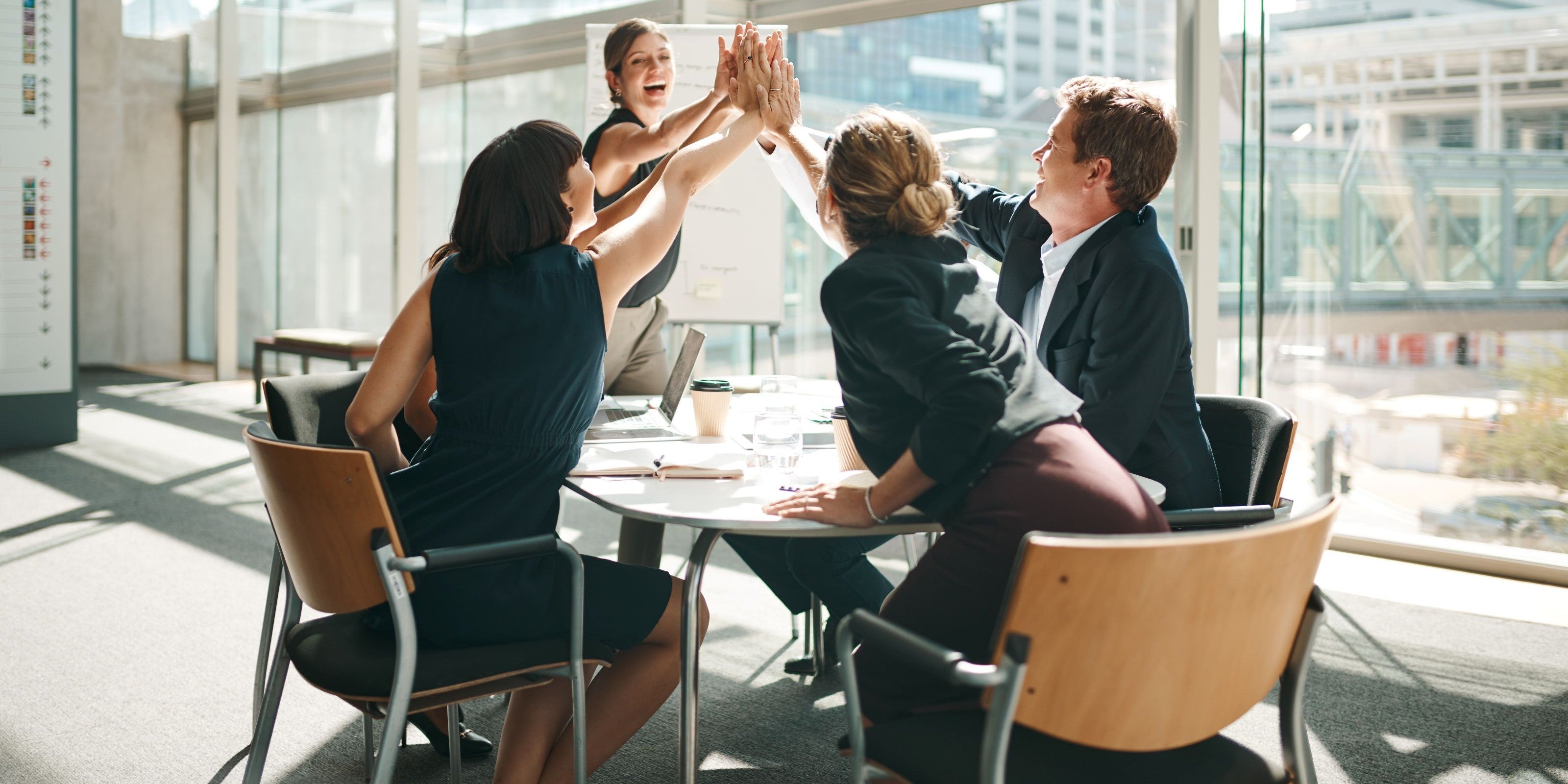 Team im Meetingraum gibt sich ein High Five