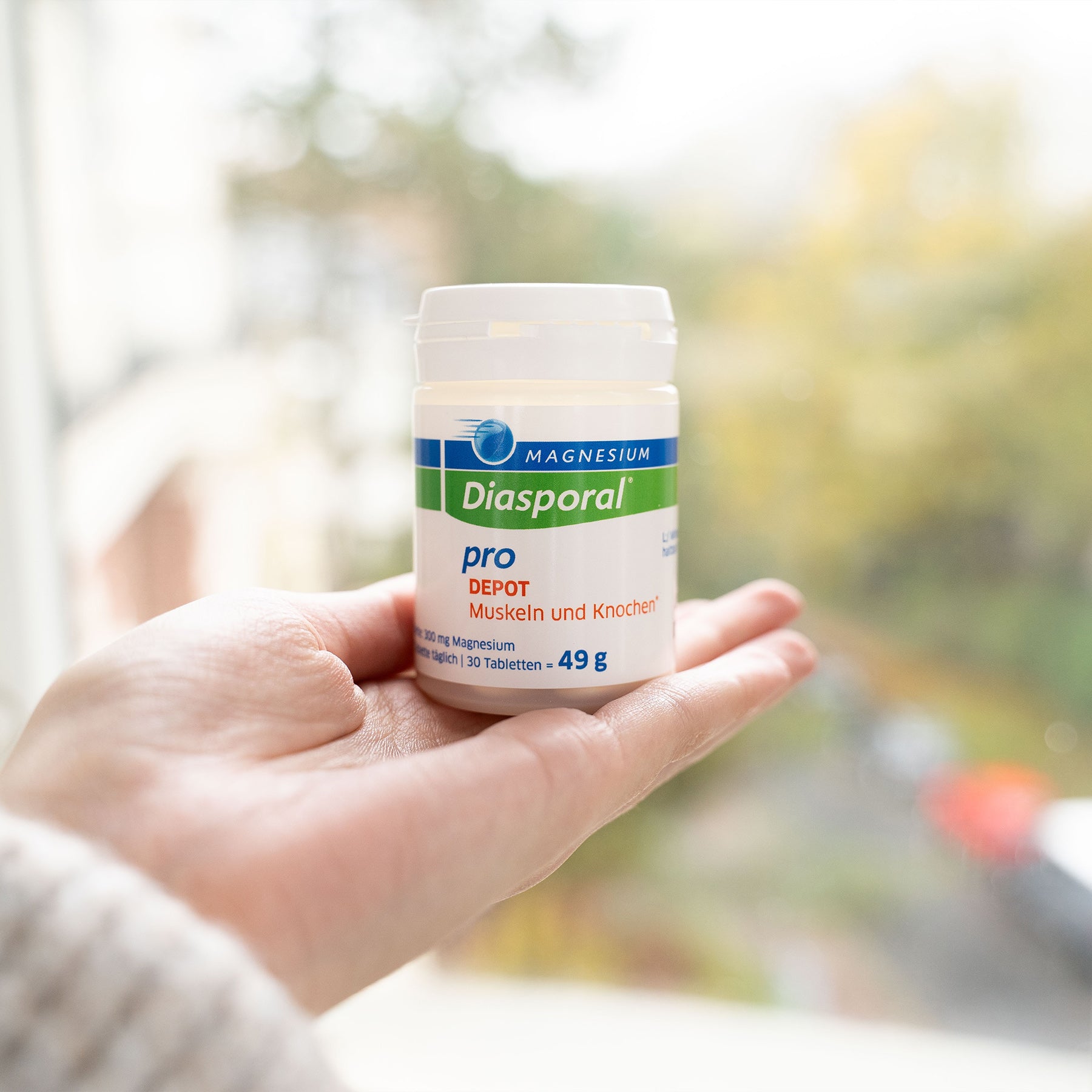 Frau hält eine Packung Magnesium-Diasporal Pro Depot Muskeln und Knochen in der Hand