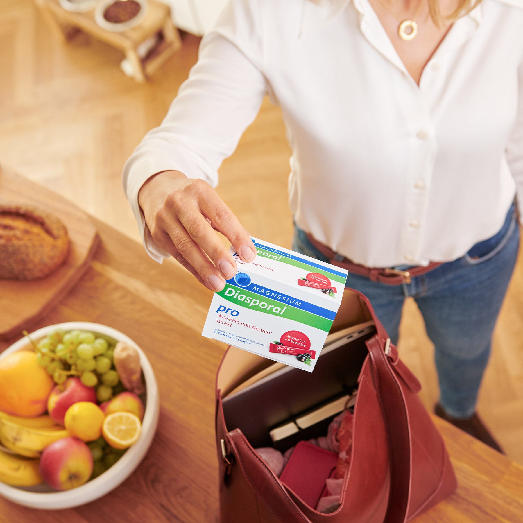 Frau legt eine Packung Magnesium-Diasporal Pro Muskeln und Nerven direkt in ihre Handtasche