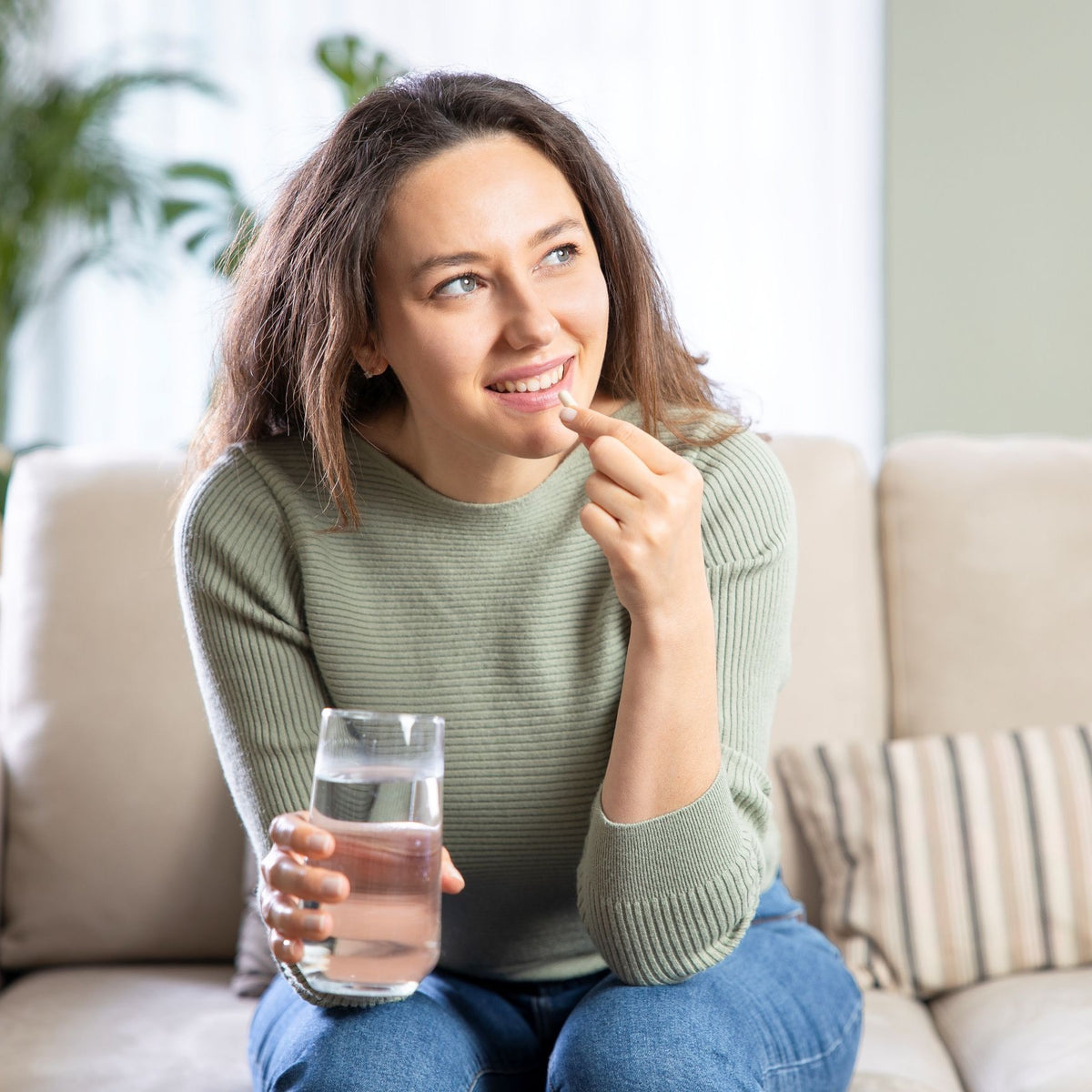 Frau nimmt eine Kapsel mit einem Glas Wasser ein