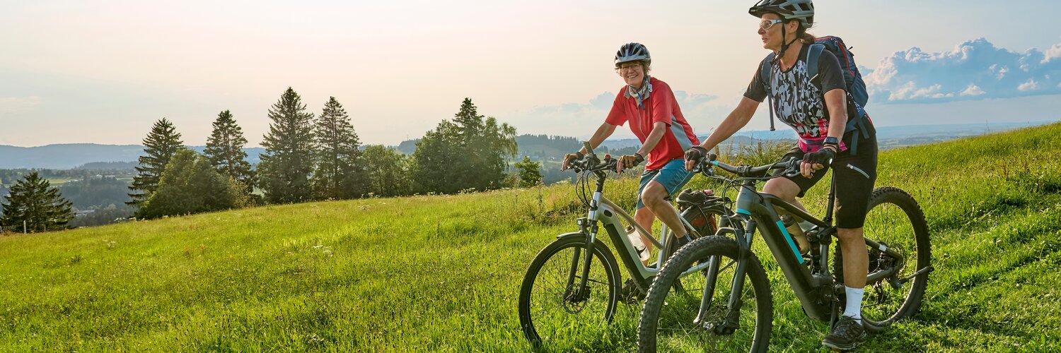 Pärchen fährt mit dem Rad über einen Wiesenweg