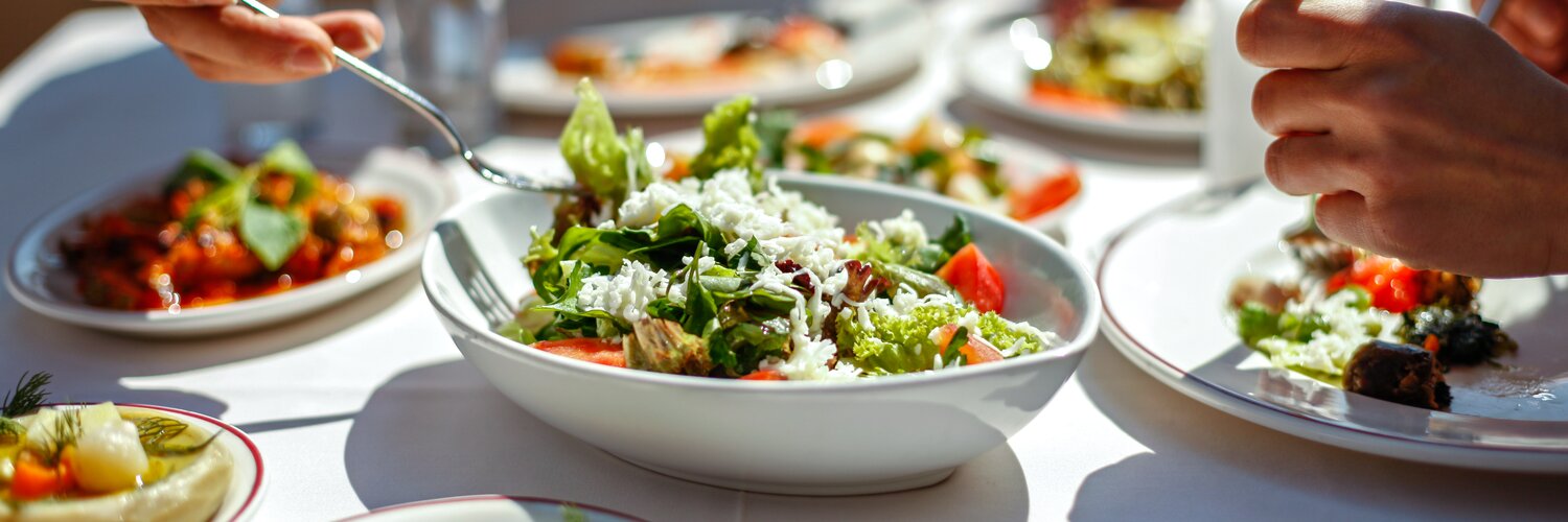 Person bedient sich an Tisch mit unterschiedlichen gesunden Speisen