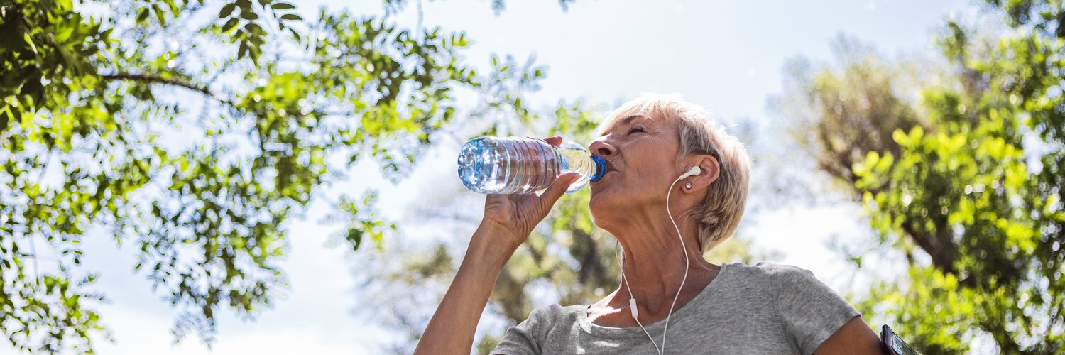 Frau trinkt beim Laufen aus ihrer Wasserflasche