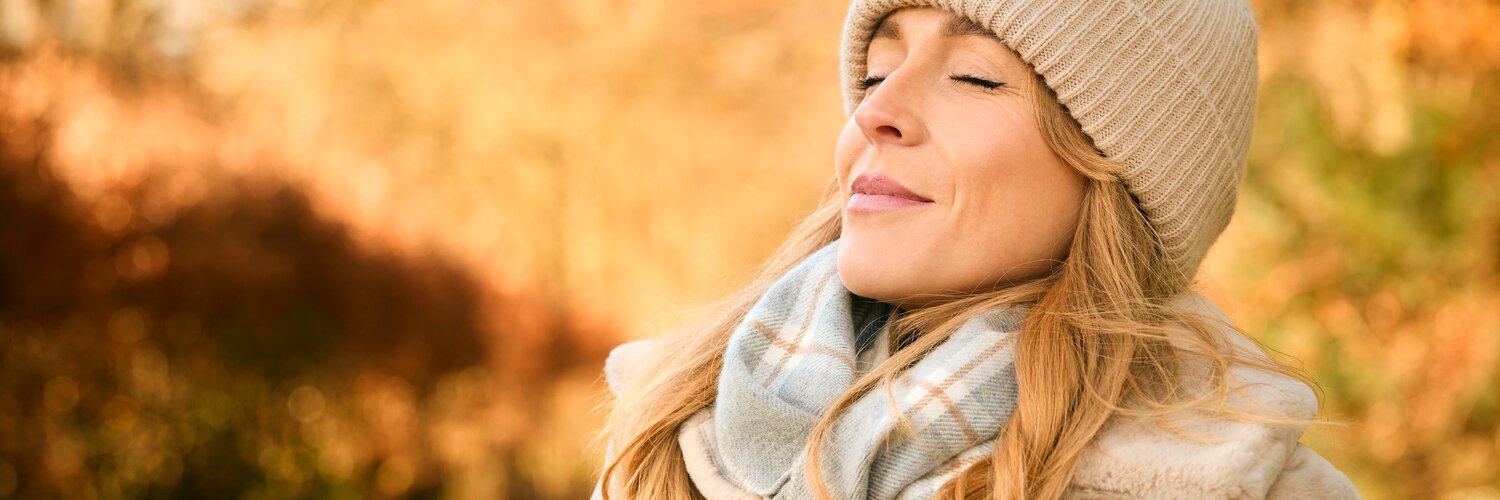 Frau atmet Herbstluft beim Spaziergang ein