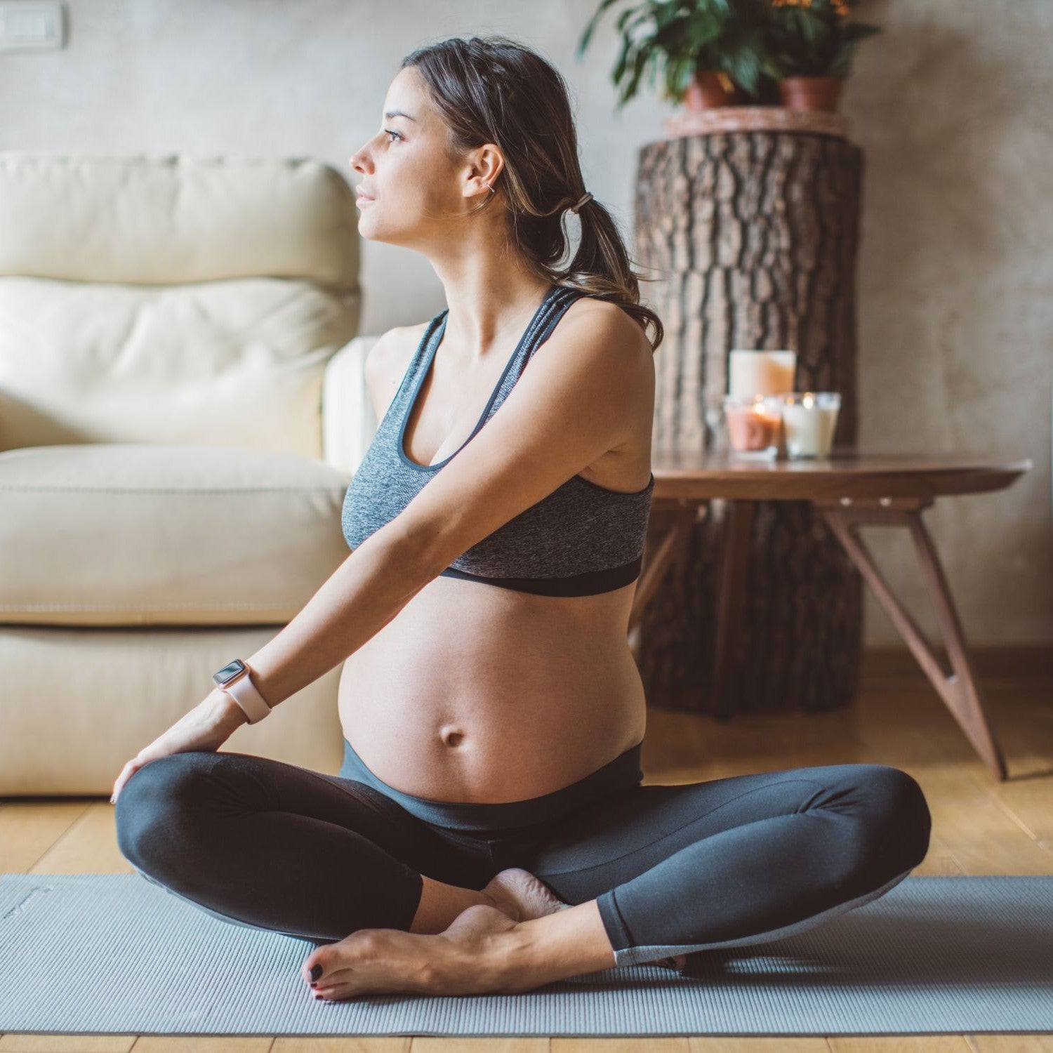 Schwangere Frau macht Yoga im Wohnzimmer