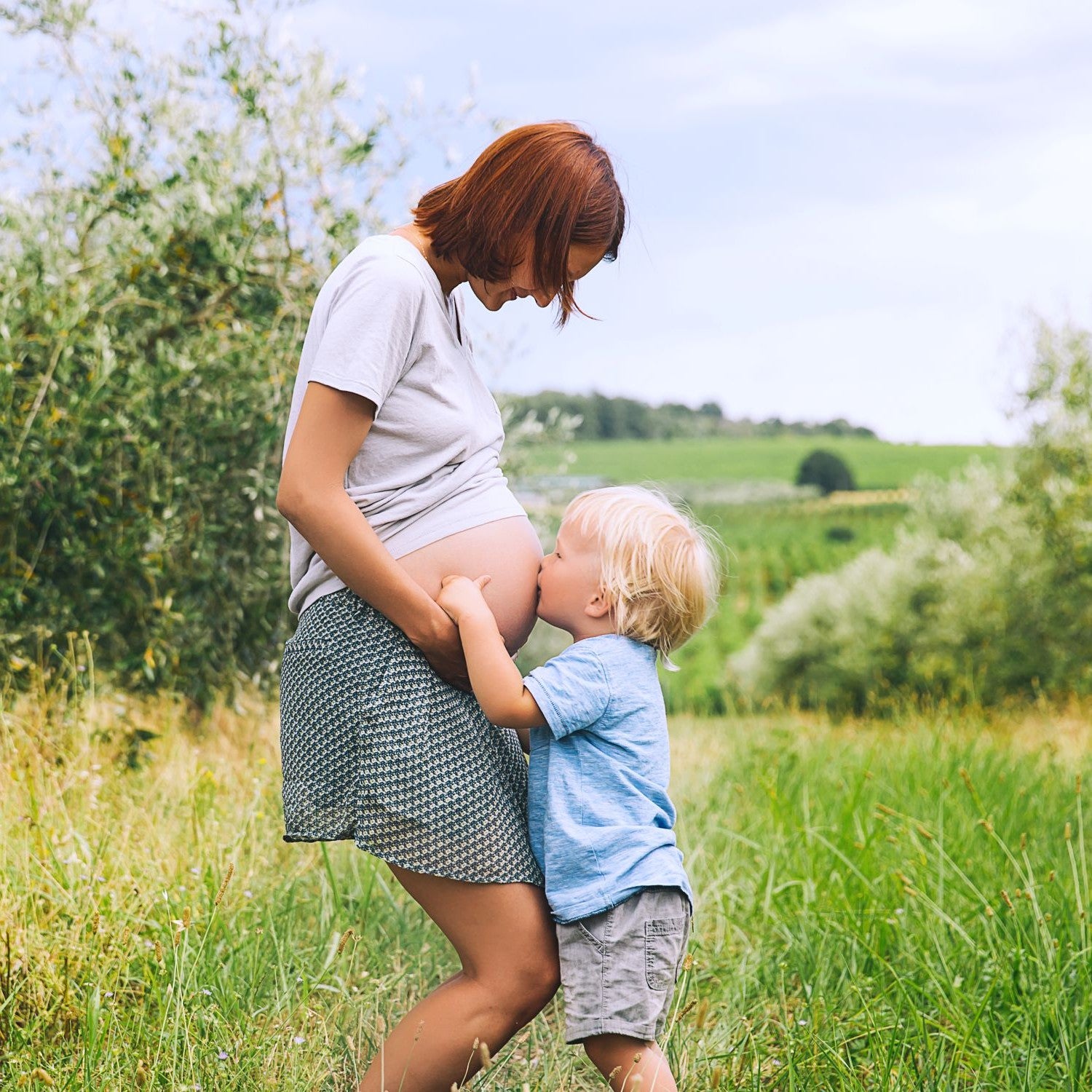 Kleiner Junge küsst den Bauch seiner schwangeren Mutter