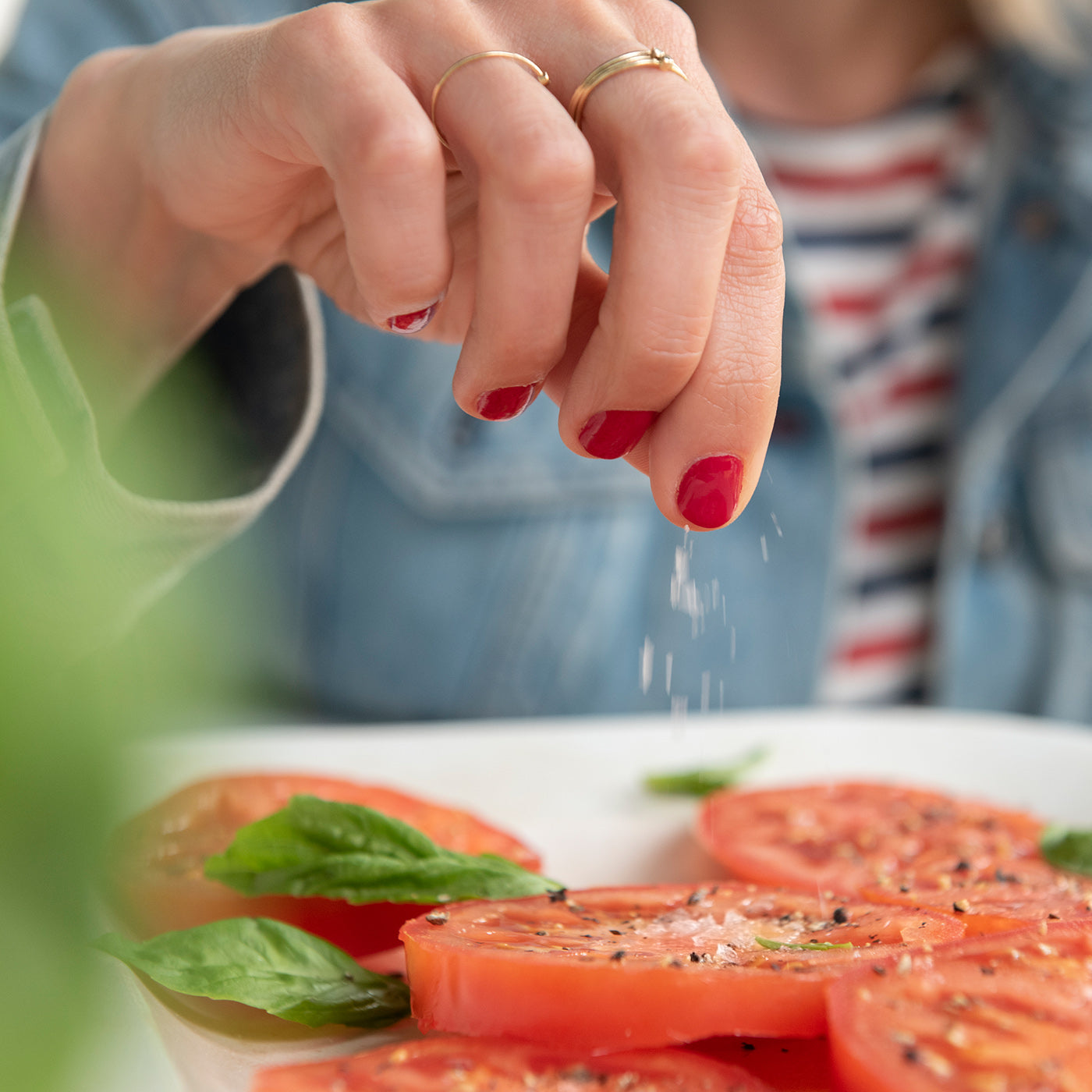 Frau würzt einen Teller mit Tomaten