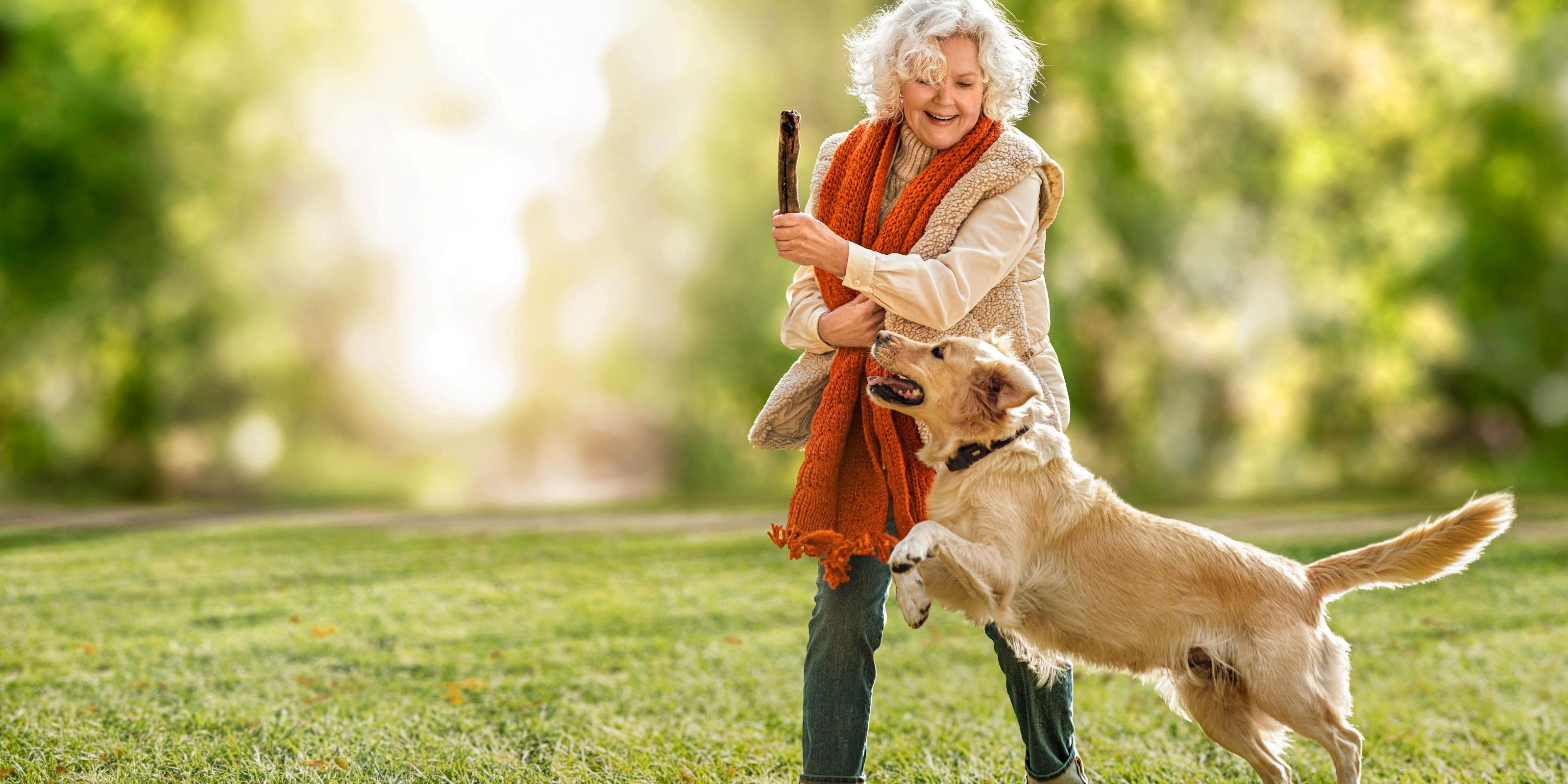 Frau spielt draußen mit ihrem Hund
