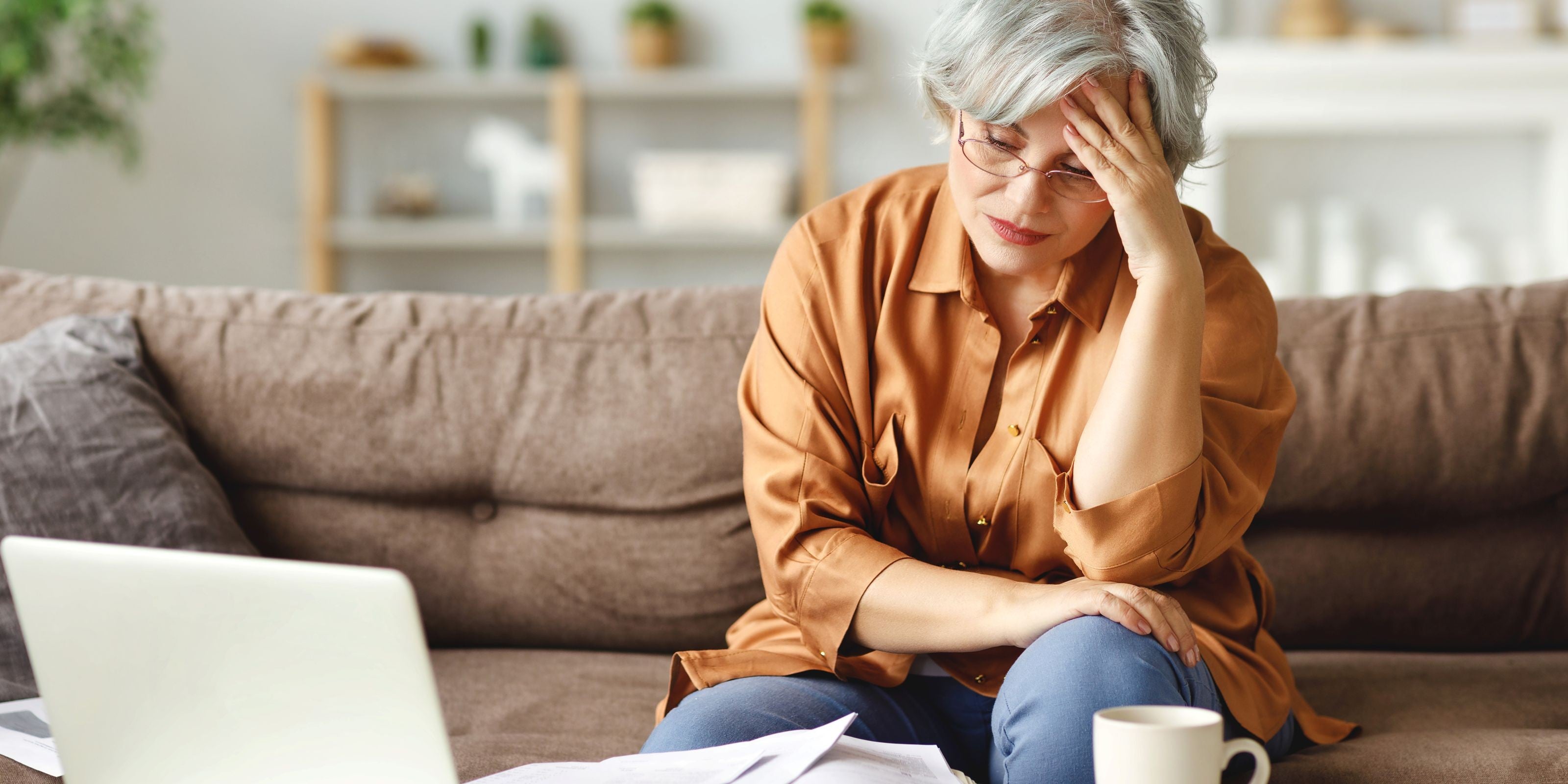 Frau sitzt auf dem Sofa und hat Kopfschmerzen