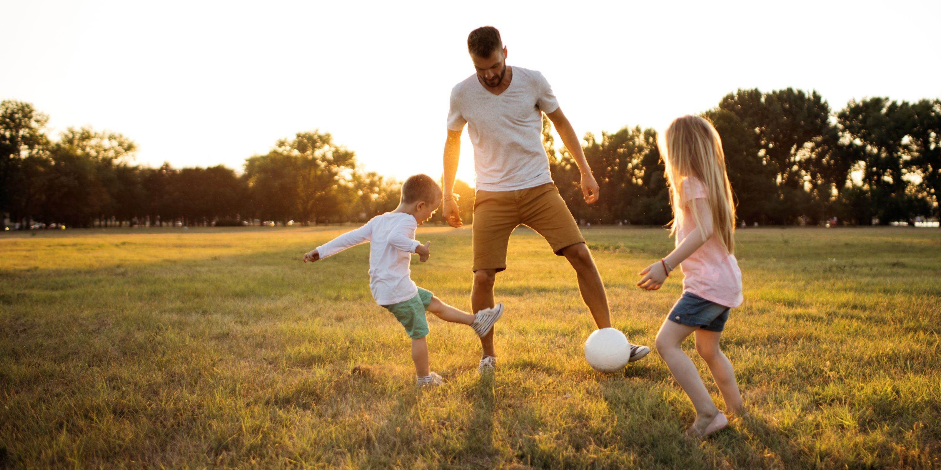 Vater spielt mit seinen Kindern Fußball