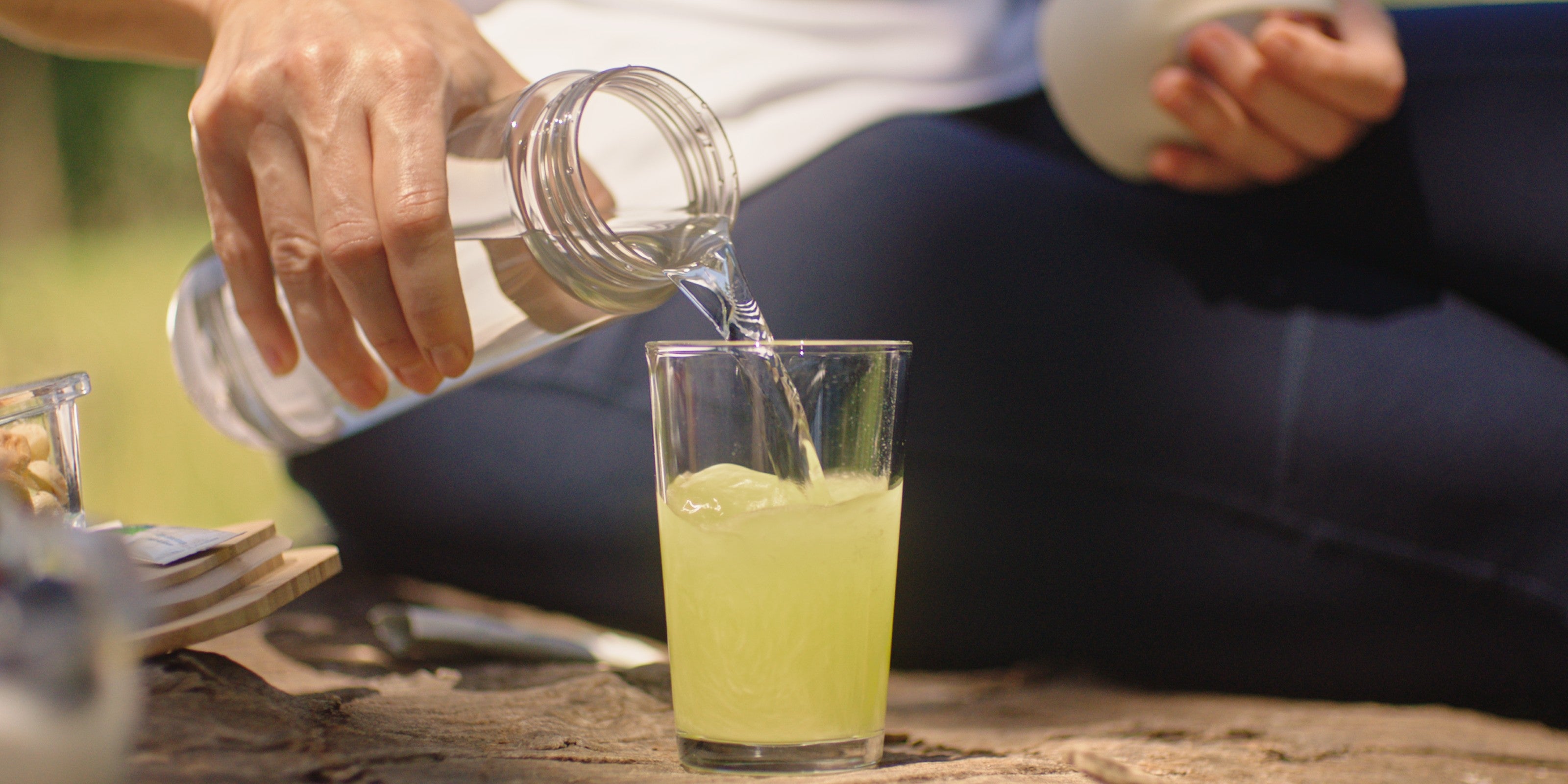 Frau schenkt Wasser in ein Glas mit einem Magnesium Trinkgranulat