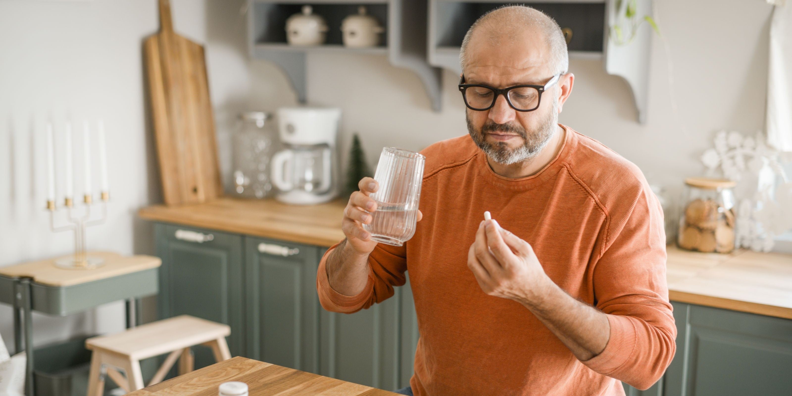 Mann nimmt Kapseln mit einem Glas Wasser ein