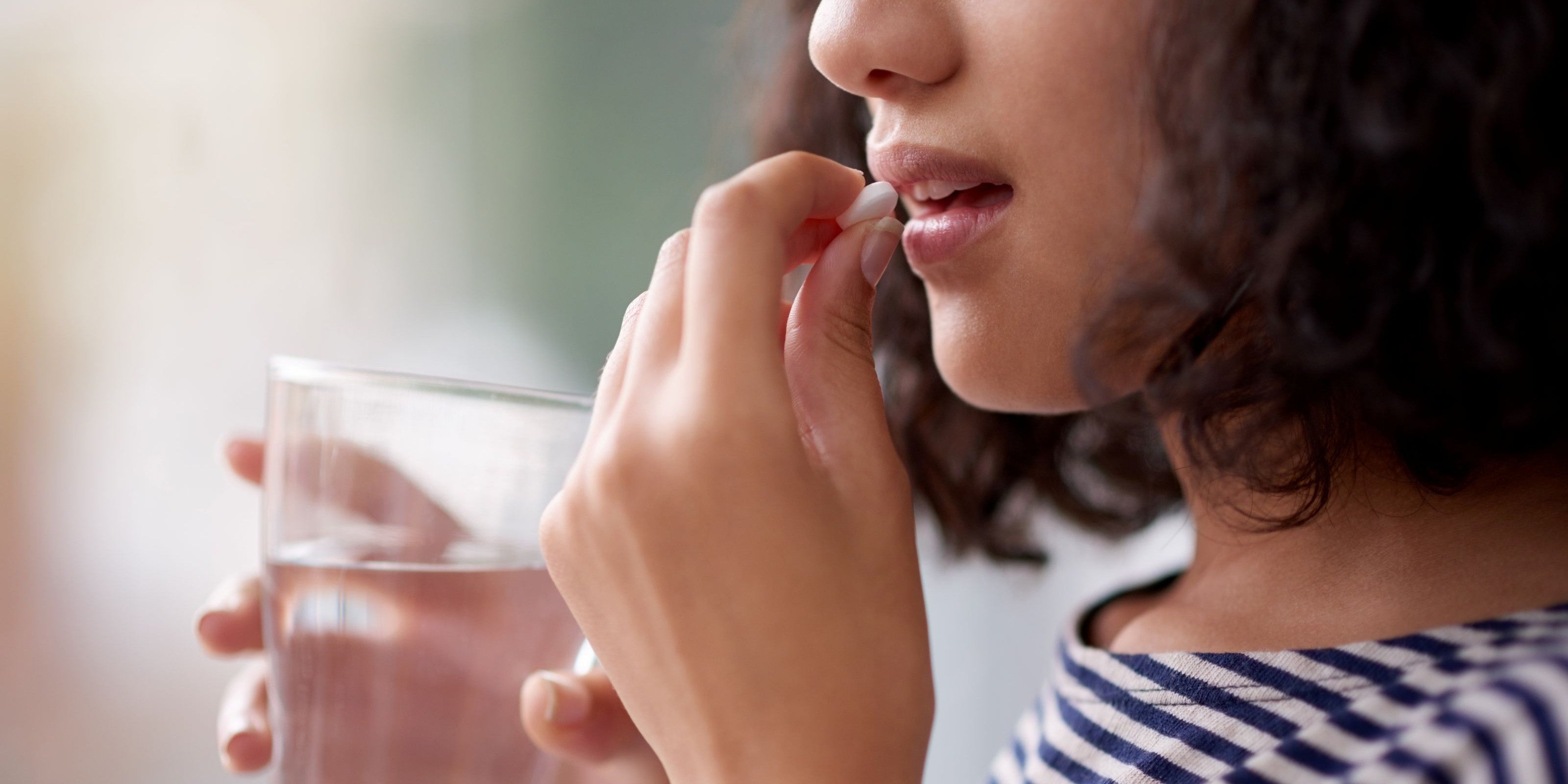 Frau nimmt eine Tablette mit Wasser ein