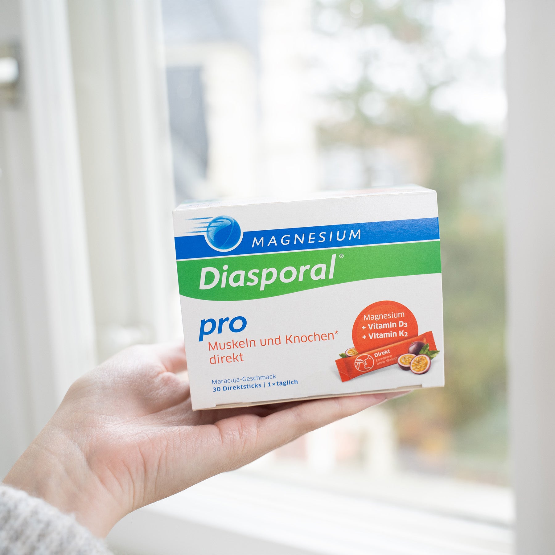 Frau hält eine Packung Magnesium-Diasporal Pro Muskeln und Knochen direkt in der Hand