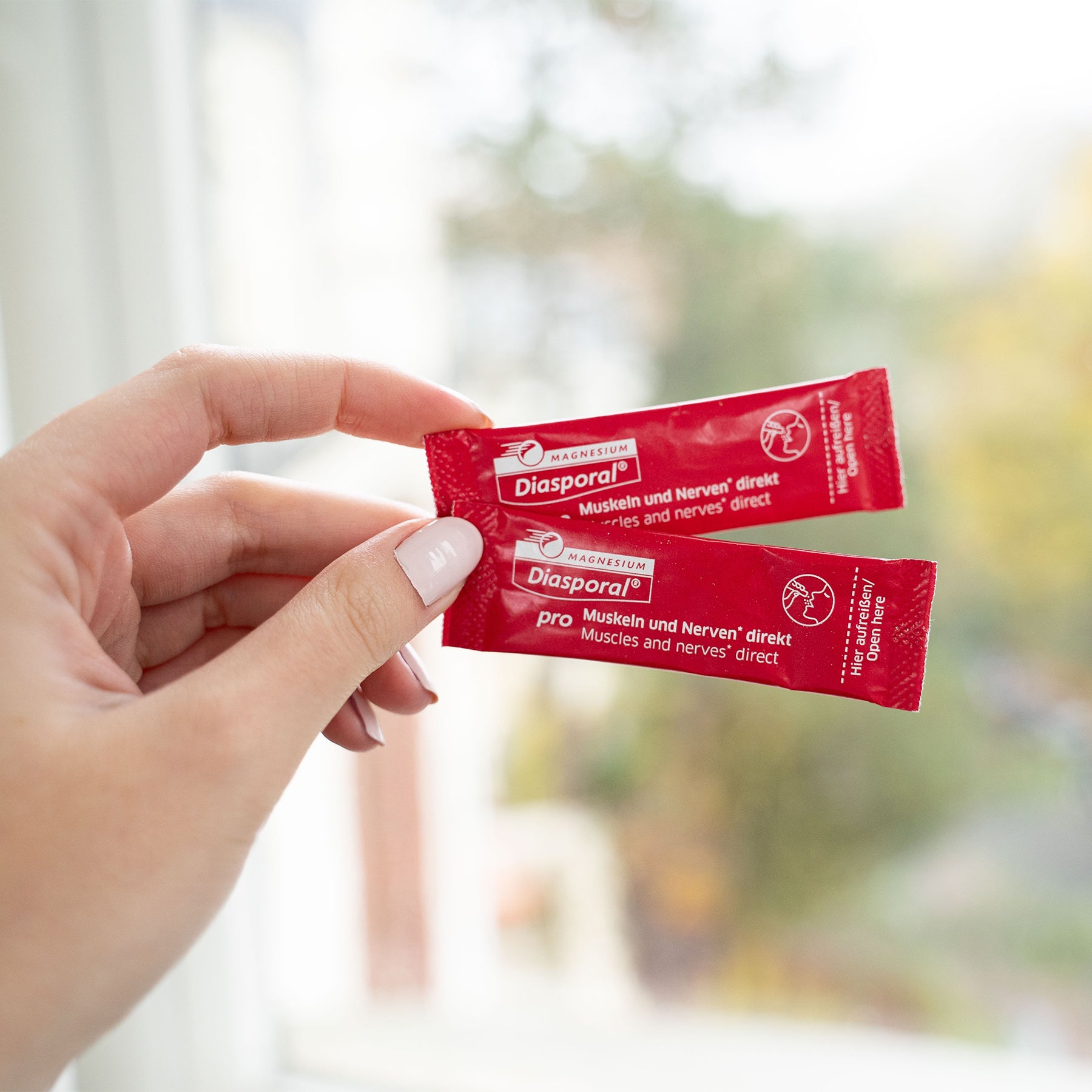 Frau hält zwei Sticks Magnesium-Diasporal Pro Muskeln und Nerven direkt in der Hand